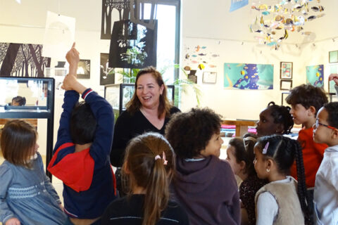 Une artiste souriante entourée d'enfants pour faire découvrir la culture